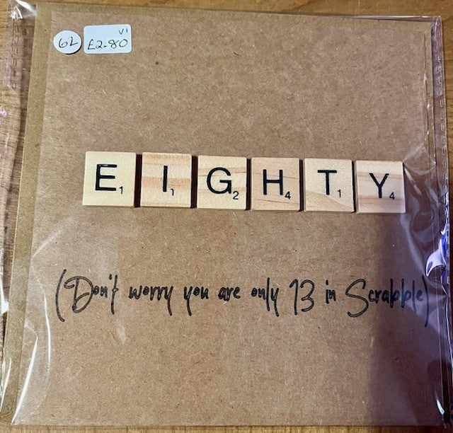 Brown greetings card with wooden tiles spelling 'EIGHTY' and a humorous note underneath.