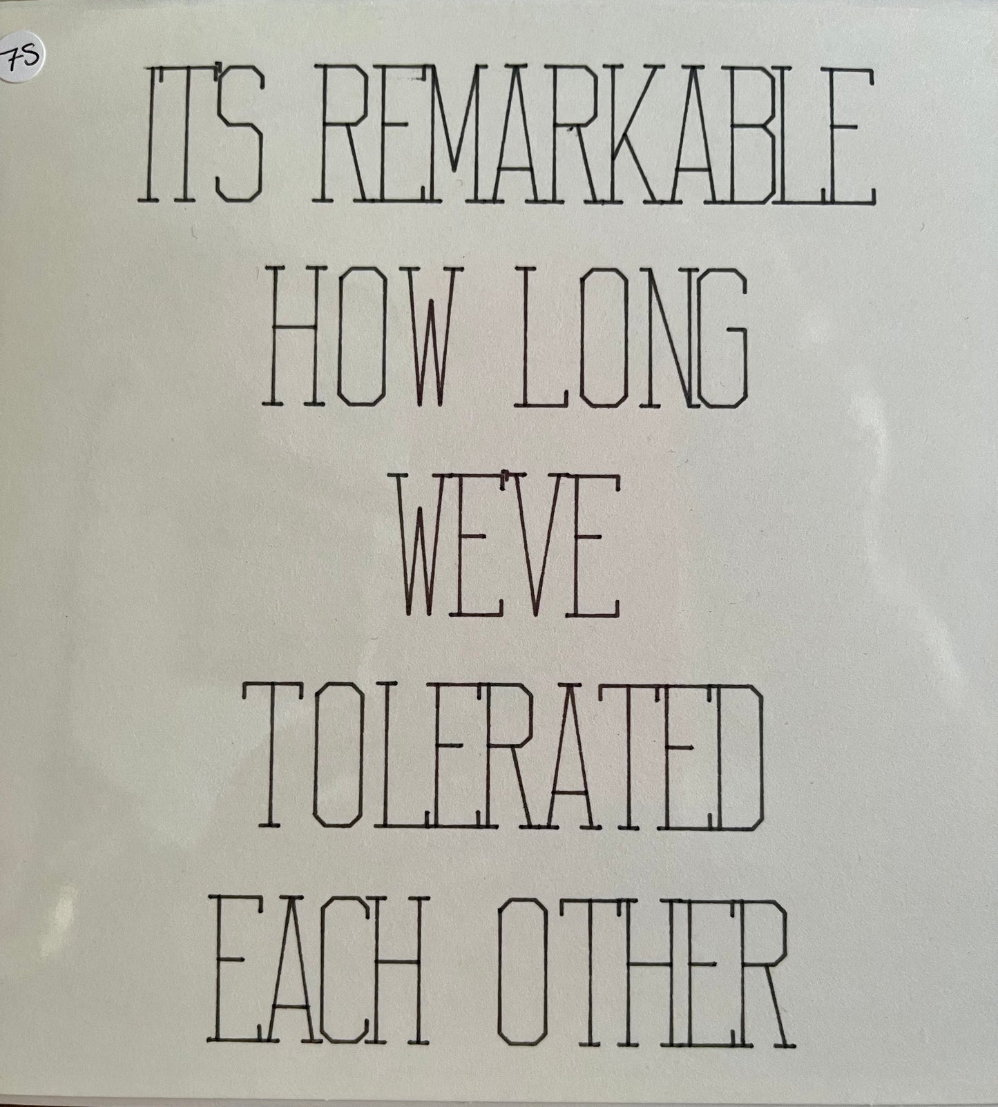 White sign with black text reading 'It's remarkable how long we've tolerated each other' on a white background.