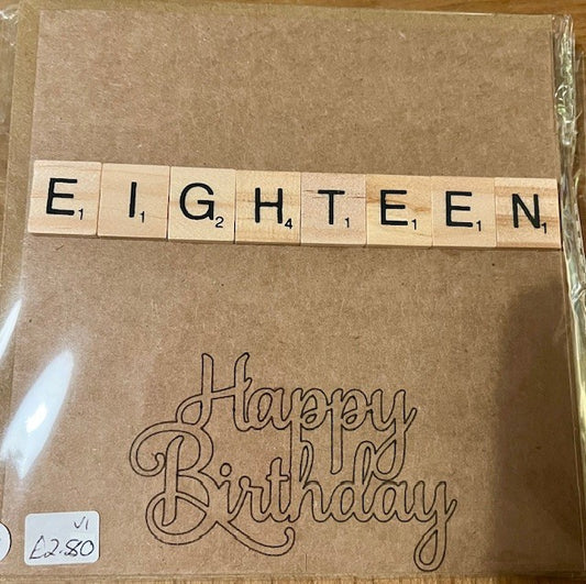 Brown greetings card with 'EIGHTEEN' spelled out using wooden tiles and 'Happy Birthday' text.