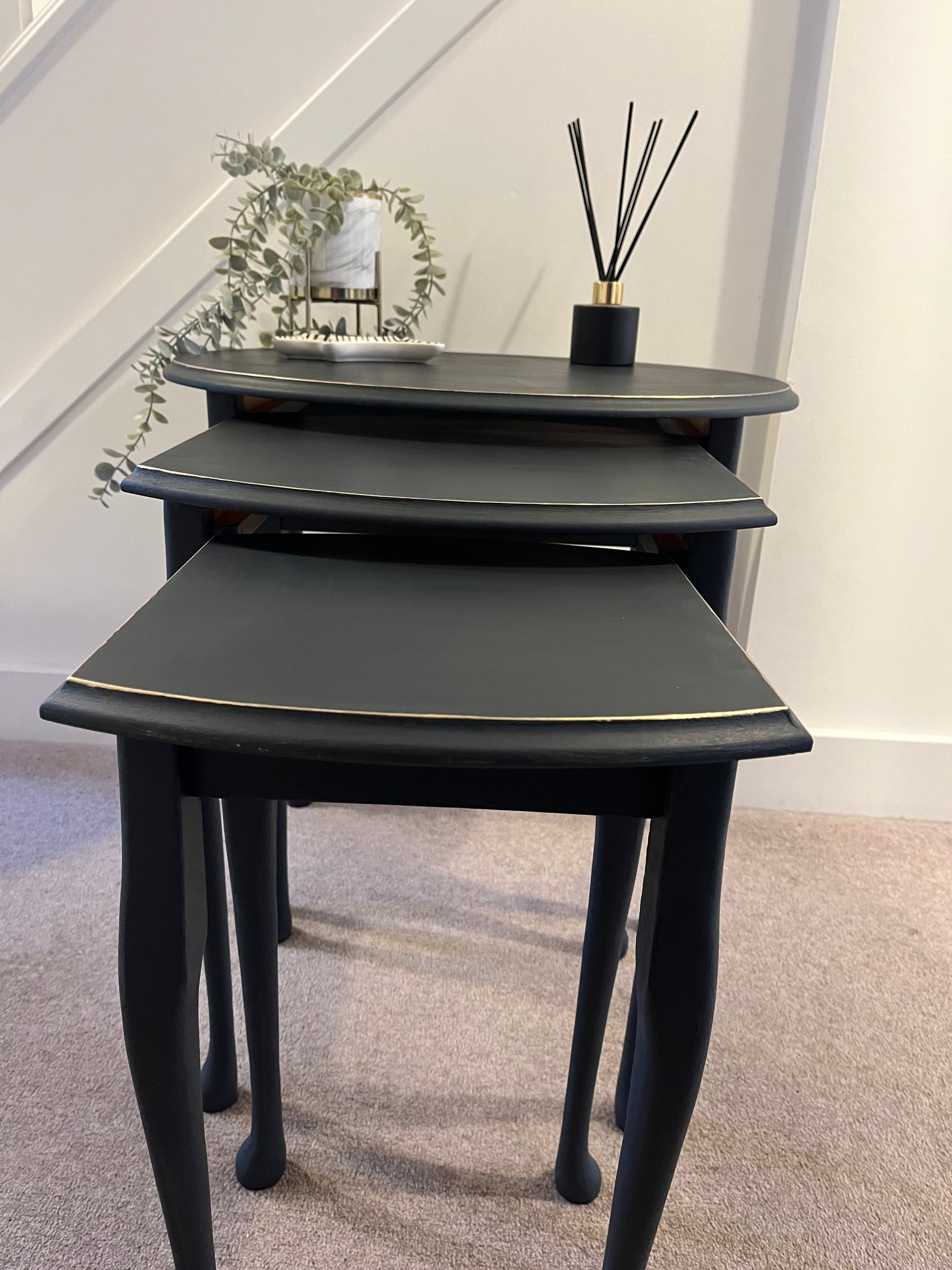 Nest of 3 black tables with gold accents.