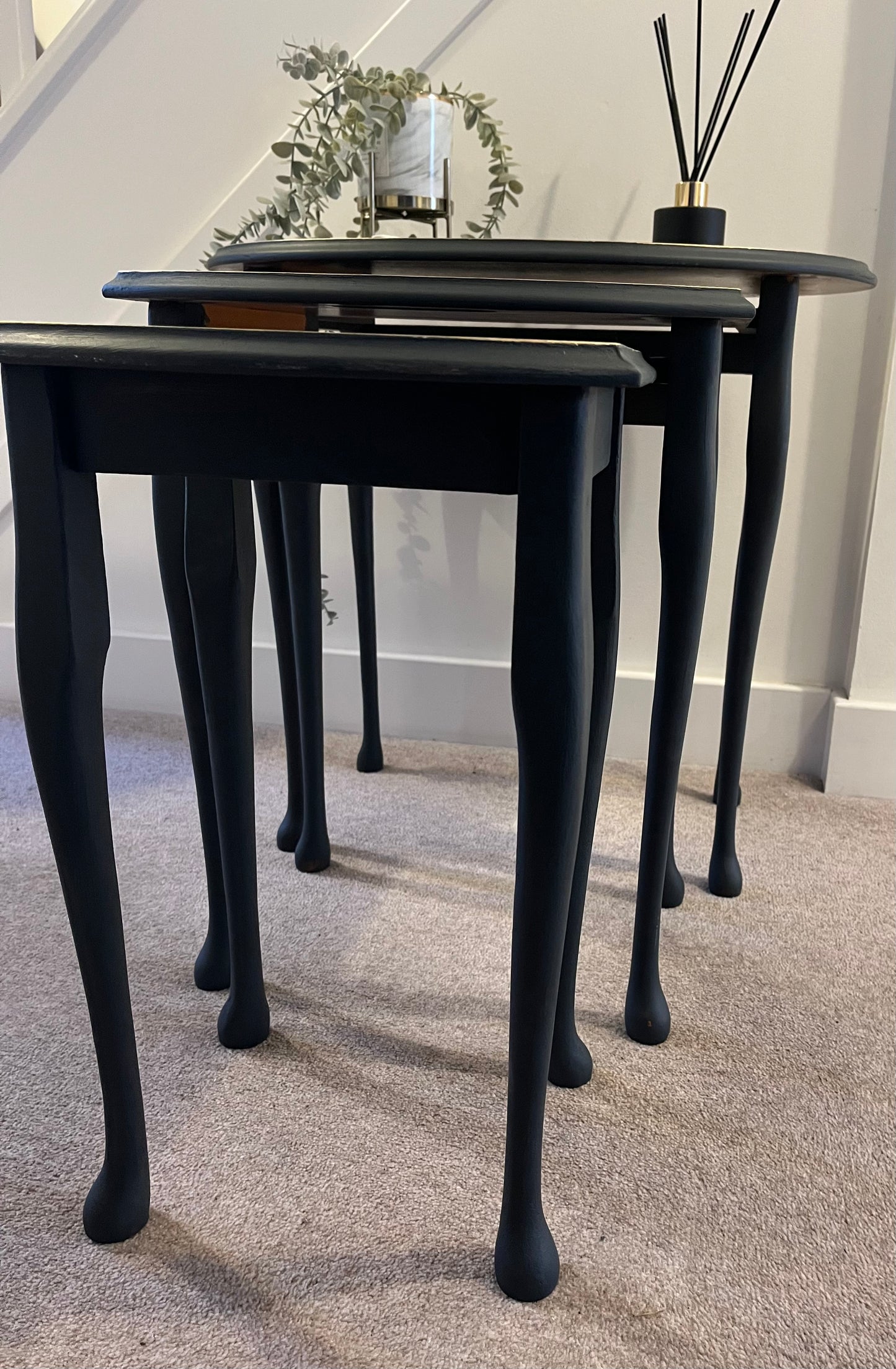 Set of black nesting tables showing long queen Anne legs.