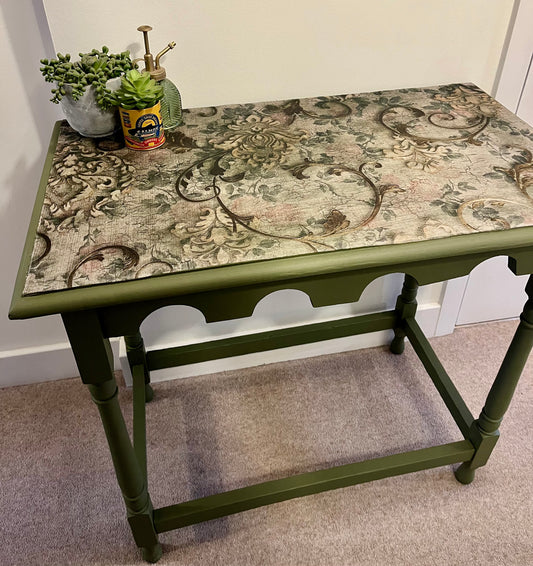 Decorative table with floral patterned top and green base.
