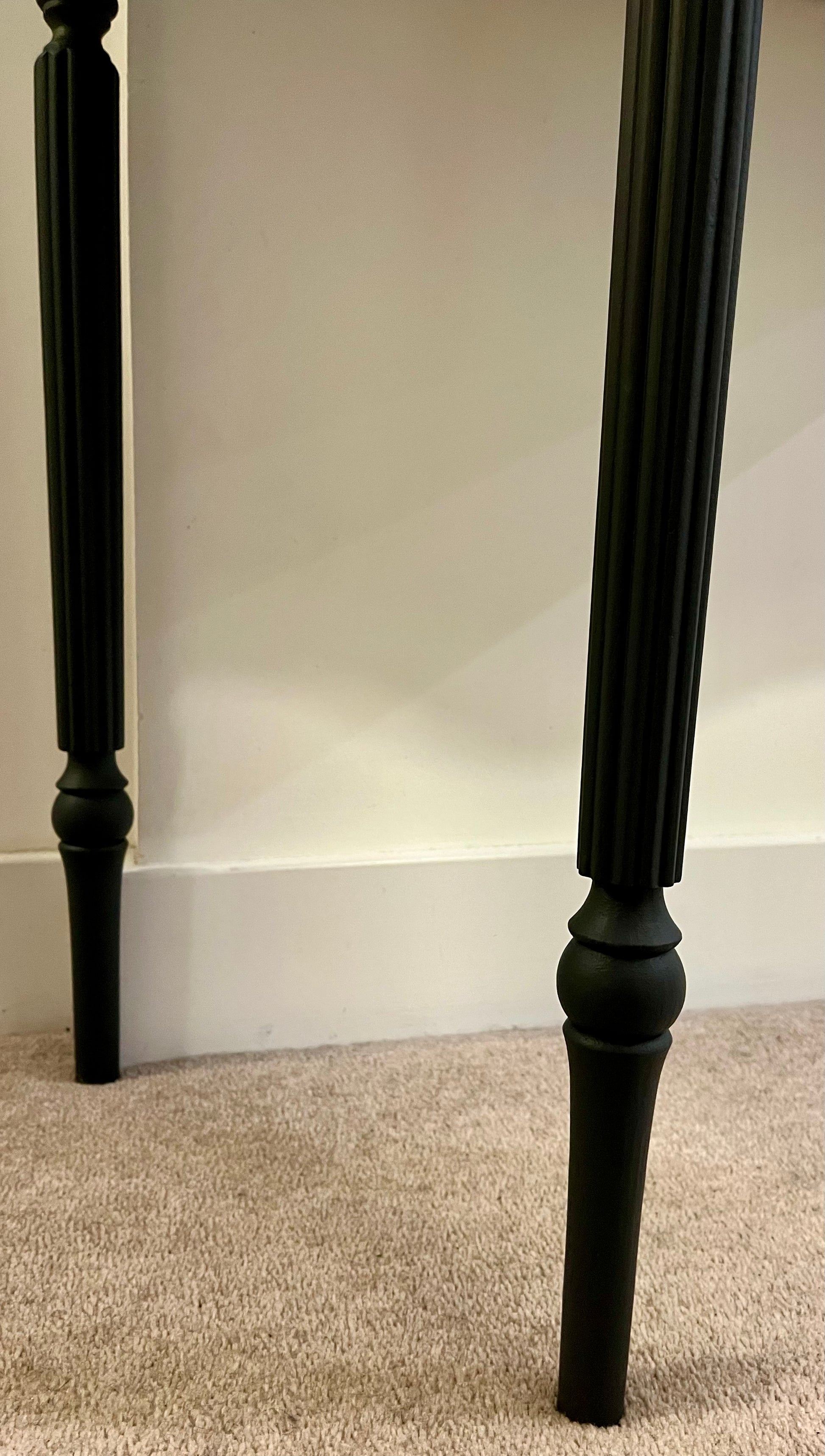 Two black wooden legs demonstrating the delicate carved detail
