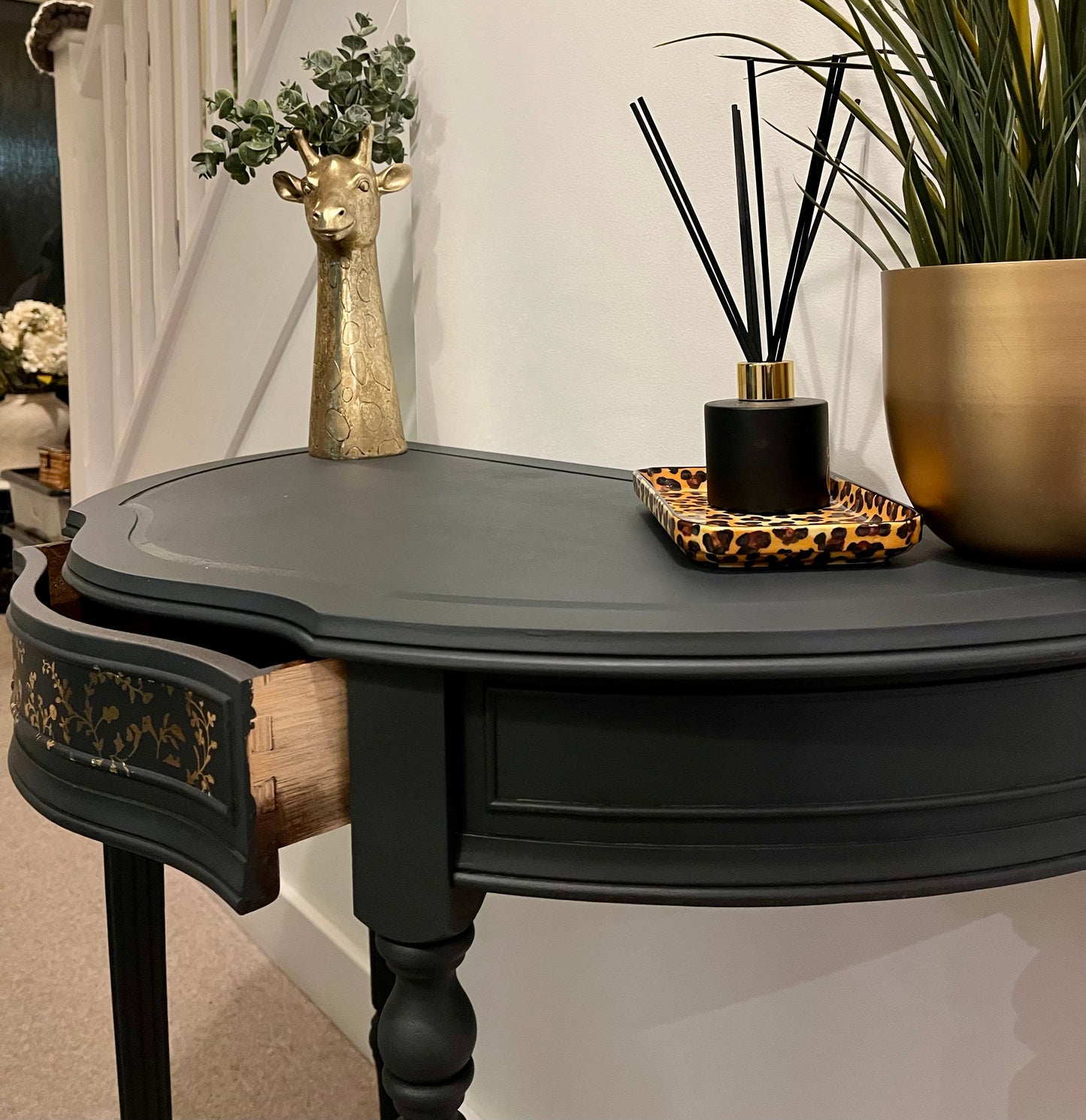 Decorative black demi lune table with drawer slightly ajar