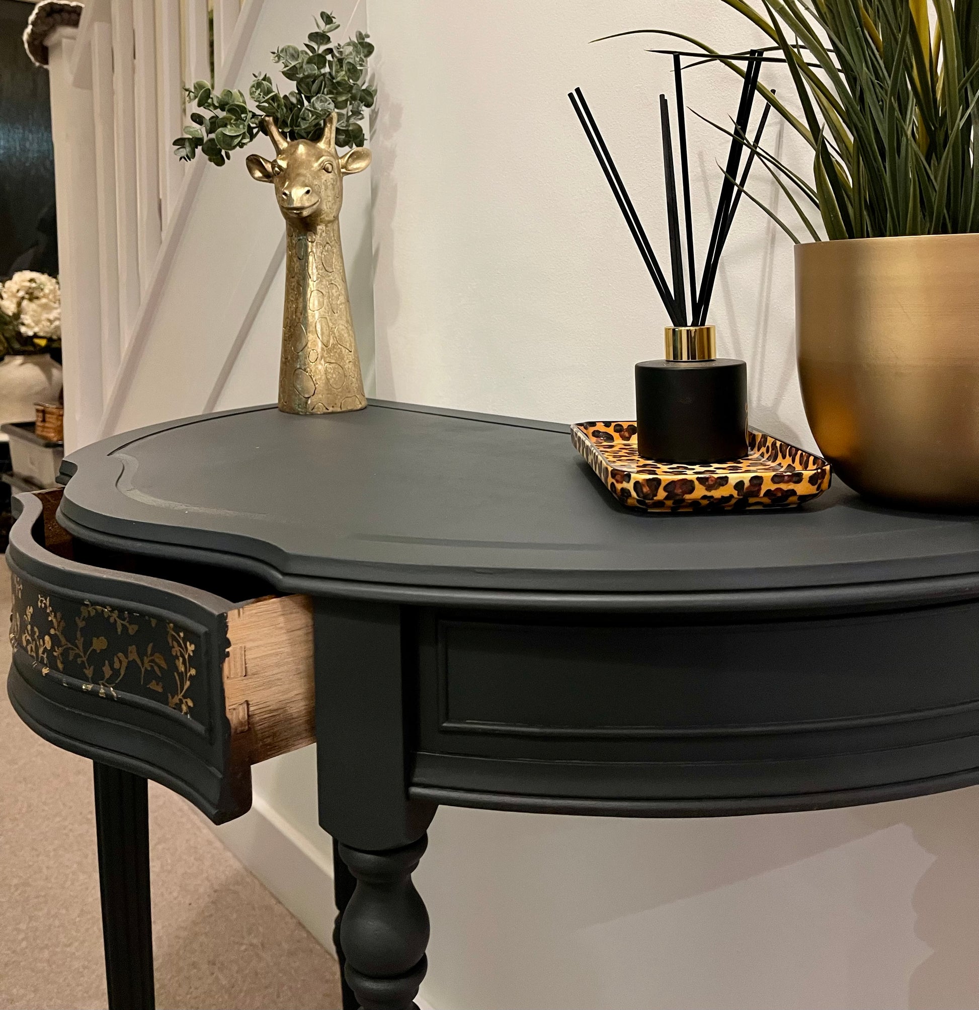 Decorative black demi lune table with drawer slightly ajar
