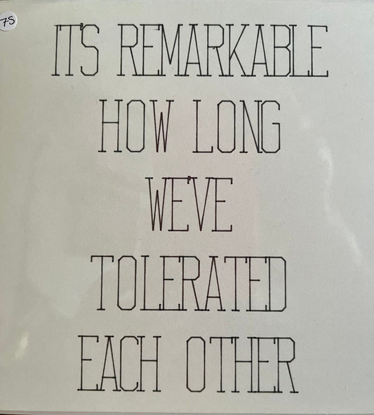 White sign with black text reading 'It's remarkable how long we've tolerated each other' on a white background.