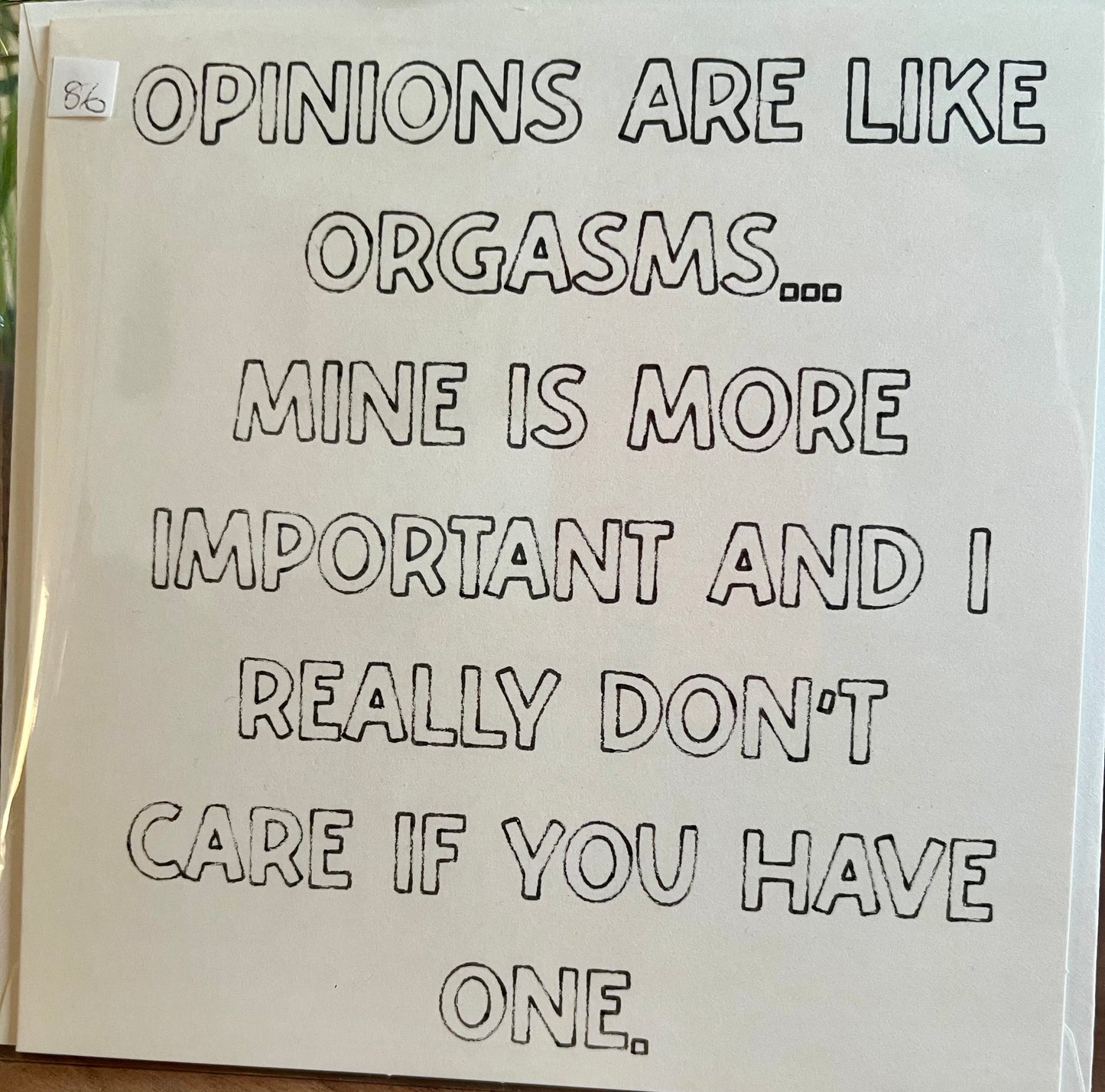 Card with humorous text about opinions being like orgasms on a plain background