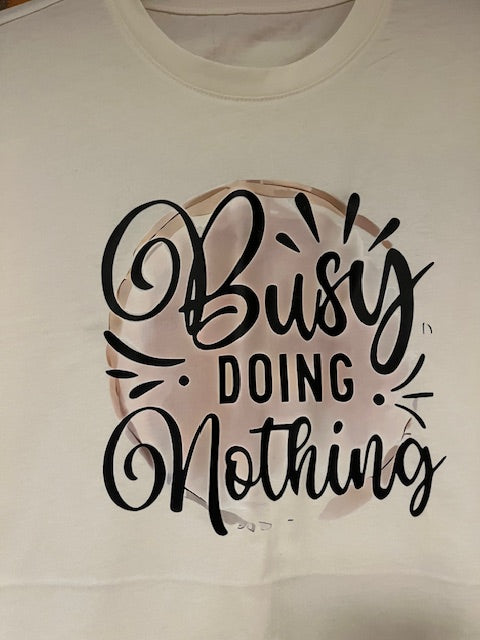 White t-shirt with black text 'BUSY DOING NOTHING' on a plain background