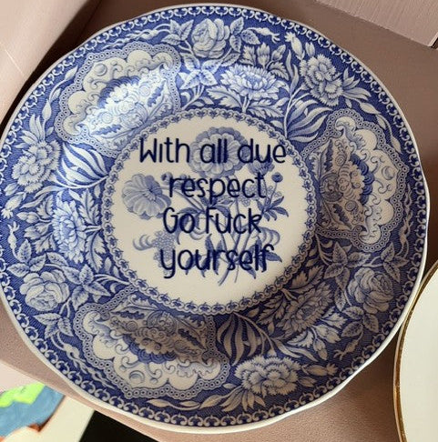 Decorative blue and white plate with offensive text.