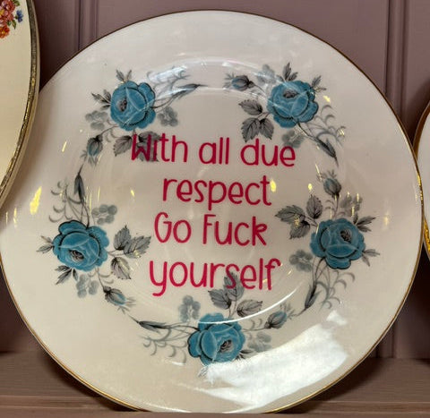 Decorative plate with floral design and offensive text on a plain background